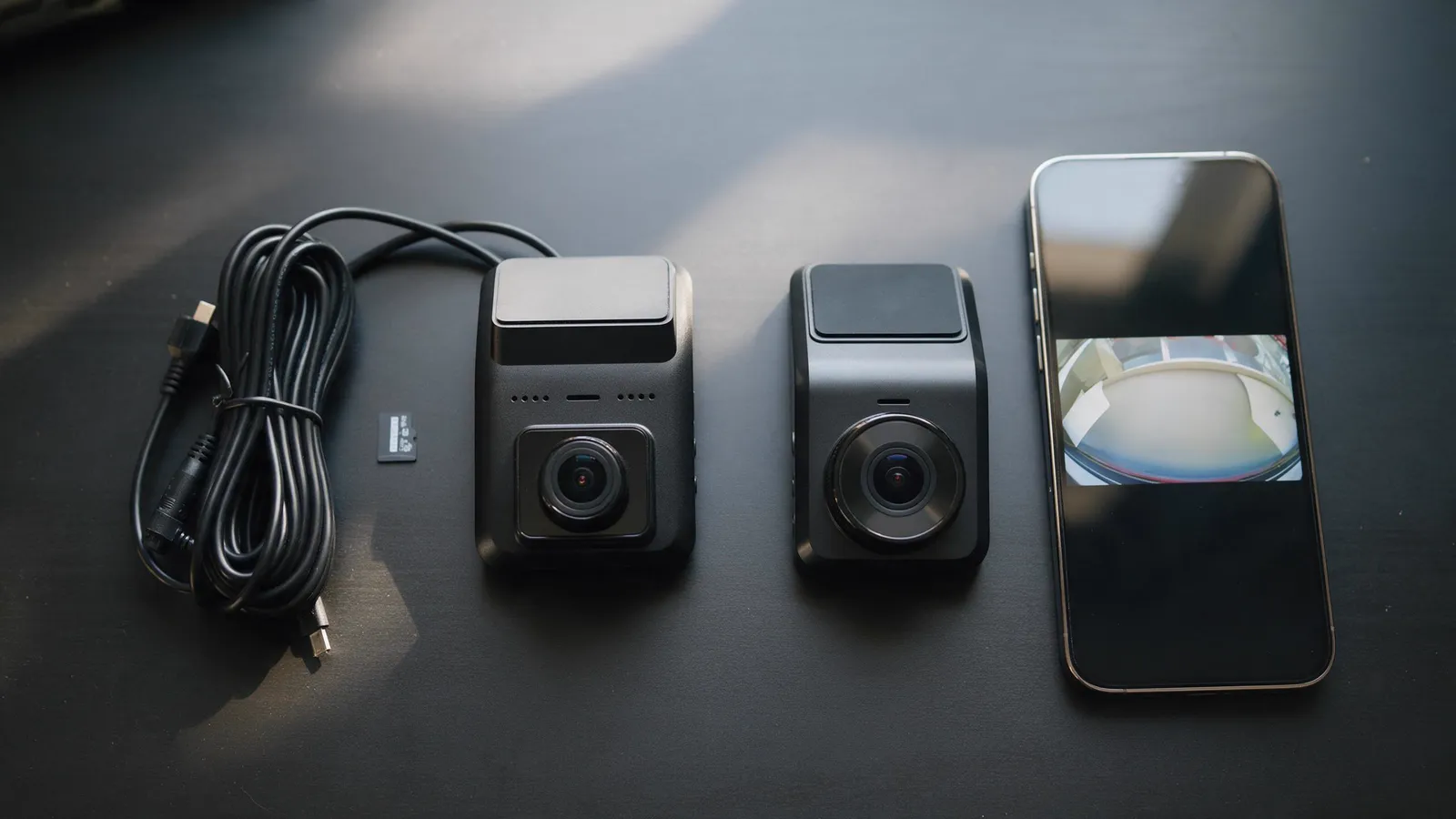Two dashcams, a power cable, a microSD card and a phone showing a live view